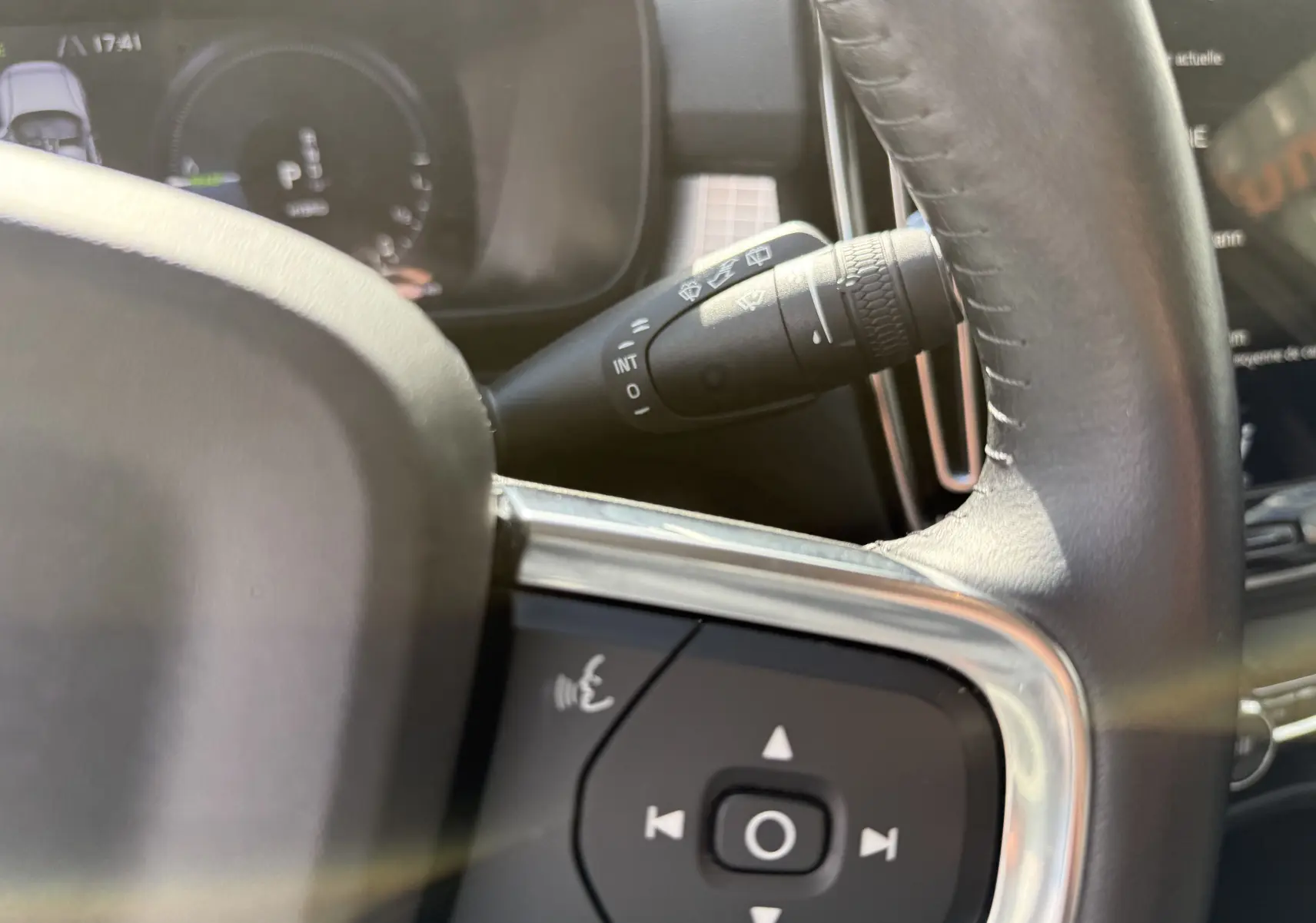Gros plan sur le volant noir et la commande des essuie-glaces du Volvo XC40 blanc Crystal Metal, version hybride rechargeable.