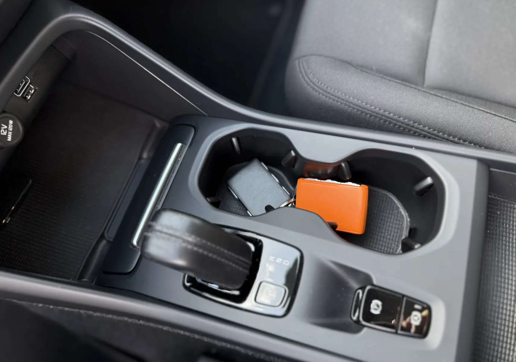 Vue rapprochée de la console centrale du Volvo XC40 blanc, montrant le levier de vitesse et porte-gobelets avec clés.