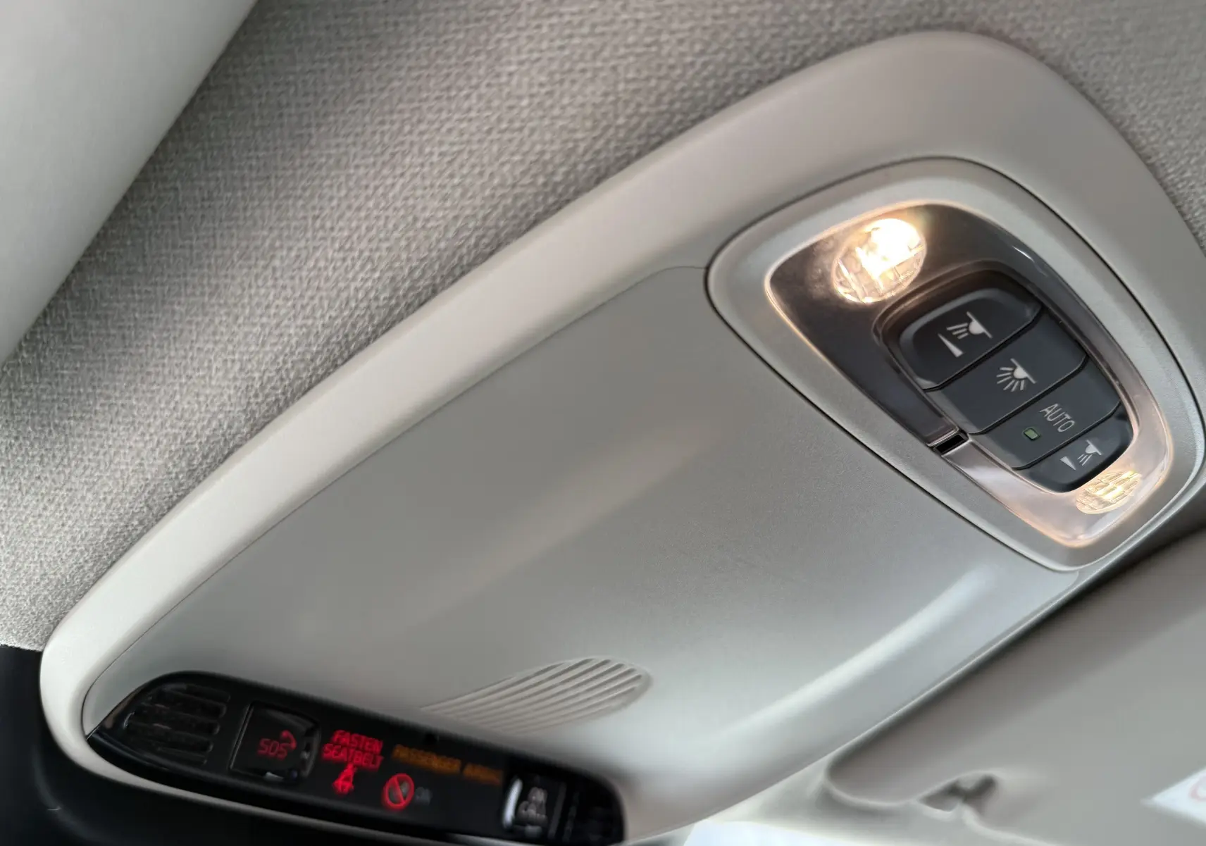 Plafonnier intérieur gris clair avec commandes d’éclairage et affichage des alertes dans un Volvo XC40 blanc Crystal Metal.