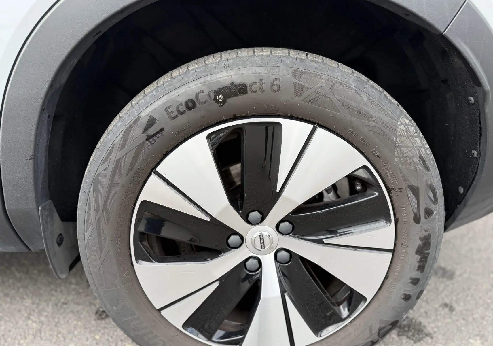 Gros plan sur la roue avant droite du Volvo XC40 blanc Crystal Metal, mettant en valeur la jante bicolore moderne.
