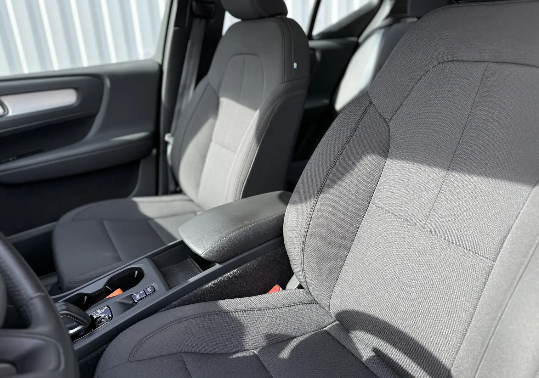 Gros plan sur les sièges avant gris tissu du Volvo XC40 T5 Plug-in Hybrid 2020, avec accoudoir central noir.