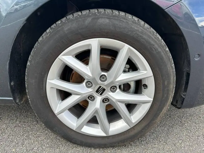 Gros plan sur la roue avant droite avec jante alu argentée de la SEAT LEON noir minuit métallisée 2025.