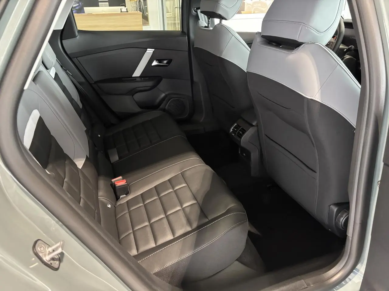 Vue intérieure arrière côté gauche de la Citroën C4 2026 avec sièges Advanced Comfort bicolores noir et gris.