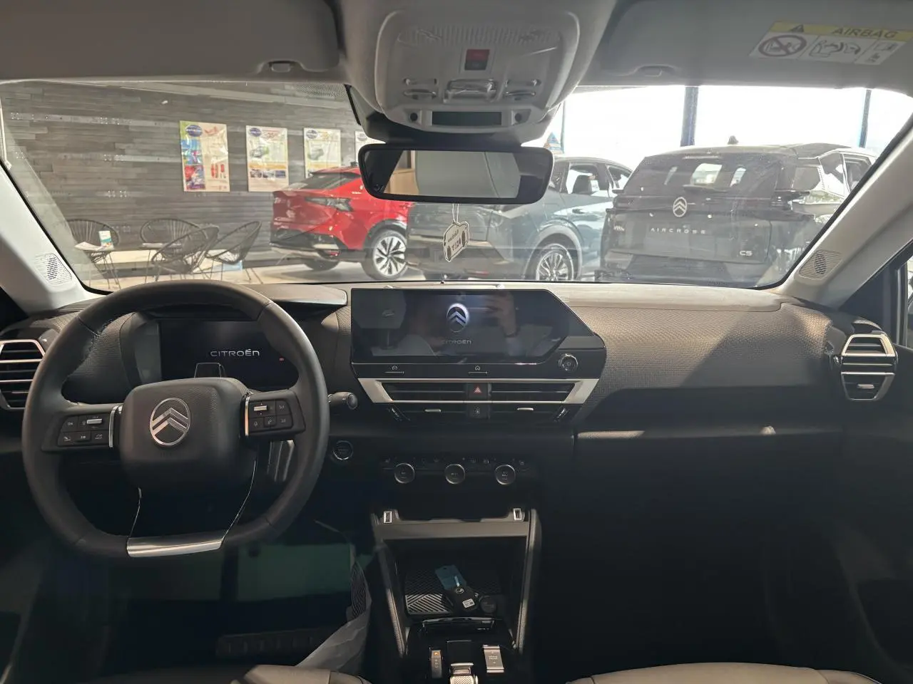 Vue intérieure avant du tableau de bord noir du Citroën C4 1.2i Hybride avec écran tactile central et volant multifonctions.