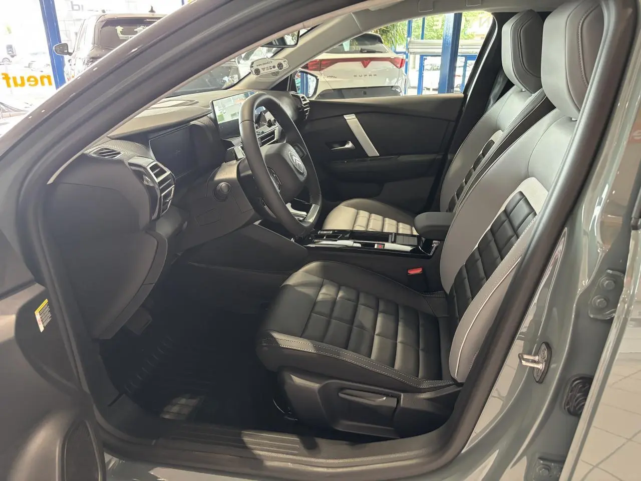 Vue intérieure côté conducteur de la Citroën C4 verte, sièges Advanced Comfort bicolores noir et gris avec console centrale brillante.