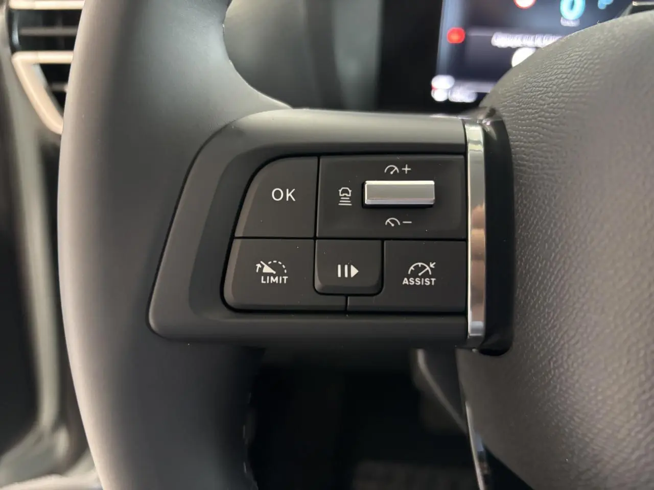 Gros plan sur les commandes multifonctions à gauche du volant noir de la Citroën C4 hybride 2026.