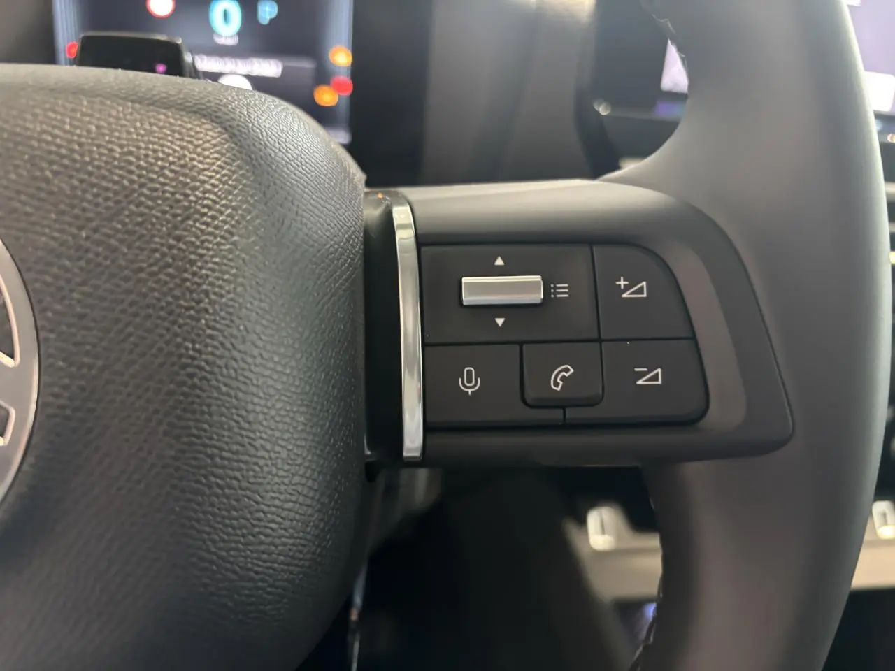 Gros plan sur les commandes vocales et téléphone à droite du volant cuir du Citroën C4 vert Manhattan Green 2026.
