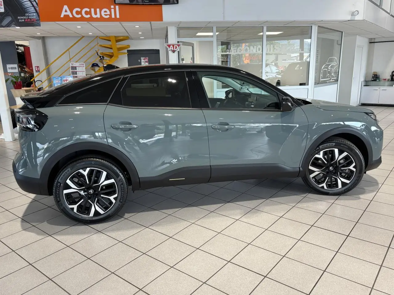 Profil côté gauche d'une Citroën C4 2026 vert Manhattan avec toit noir Perla Nera en showroom.