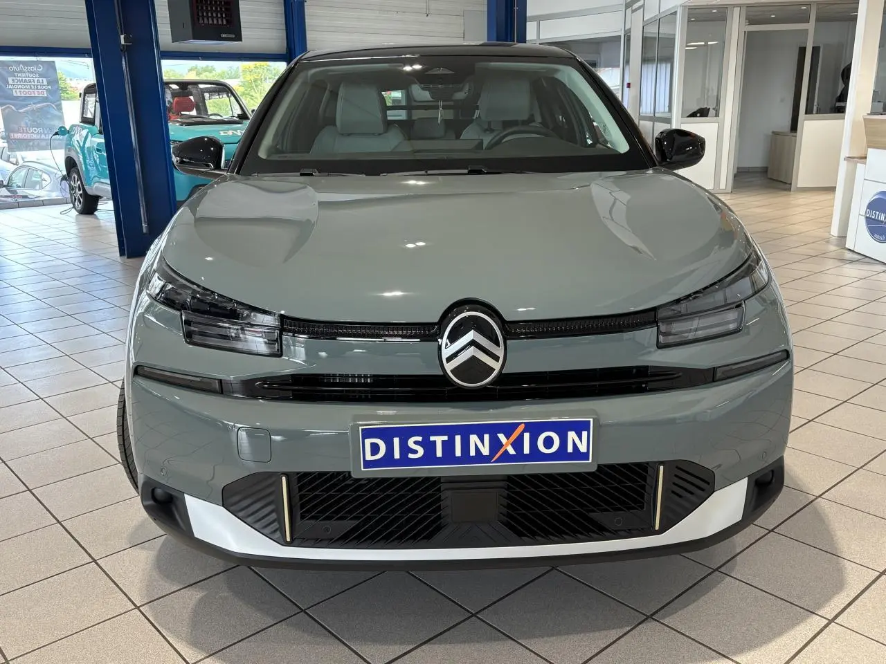 Vue avant d'une Citroën C4 2026 vert Manhattan avec toit noir et calandre noire brillante en showroom.