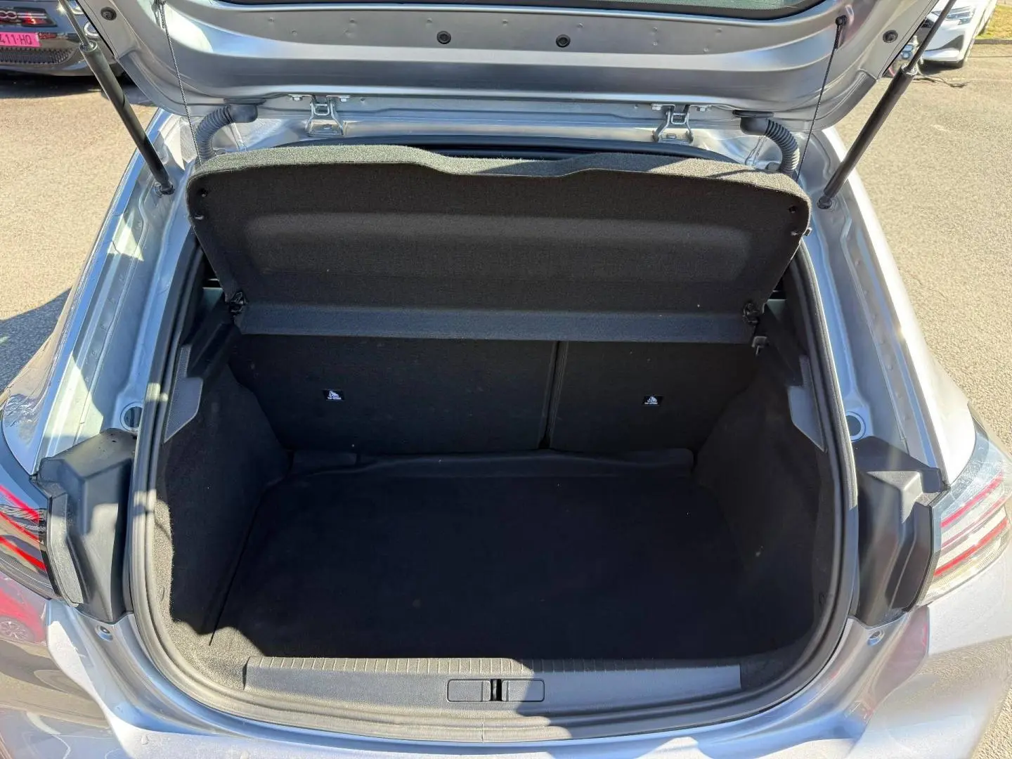 Coffre ouvert vu de dessus d'une Peugeot 208 gris Artense, montrant un espace de chargement propre et vide.
