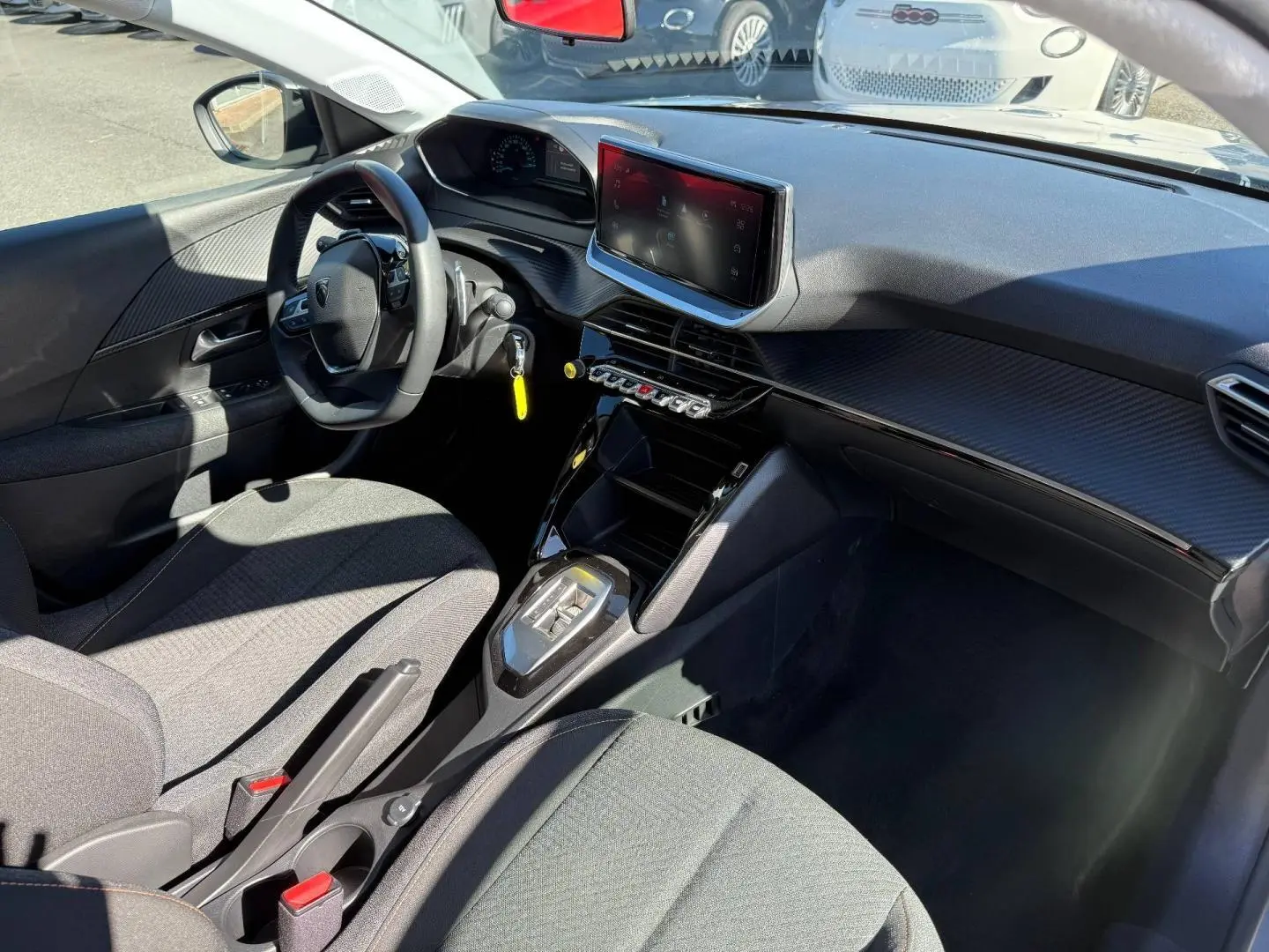 Vue intérieure côté conducteur de la Peugeot 208 gris Artense, avec tableau de bord moderne et écran tactile central.