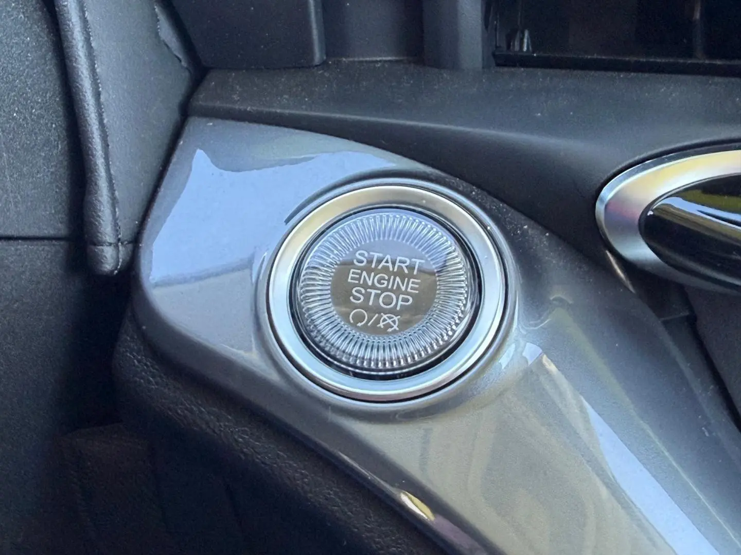 Gros plan sur le bouton Start Engine Stop dans l'habitacle de la Fiat 500 e Ocean Green métal 2024.