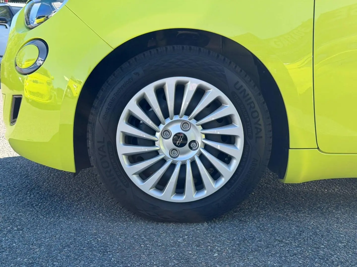 Gros plan sur la roue avant gauche d’une FIAT 500 électrique Ocean Green métal avec jante argentée à rayons fins.