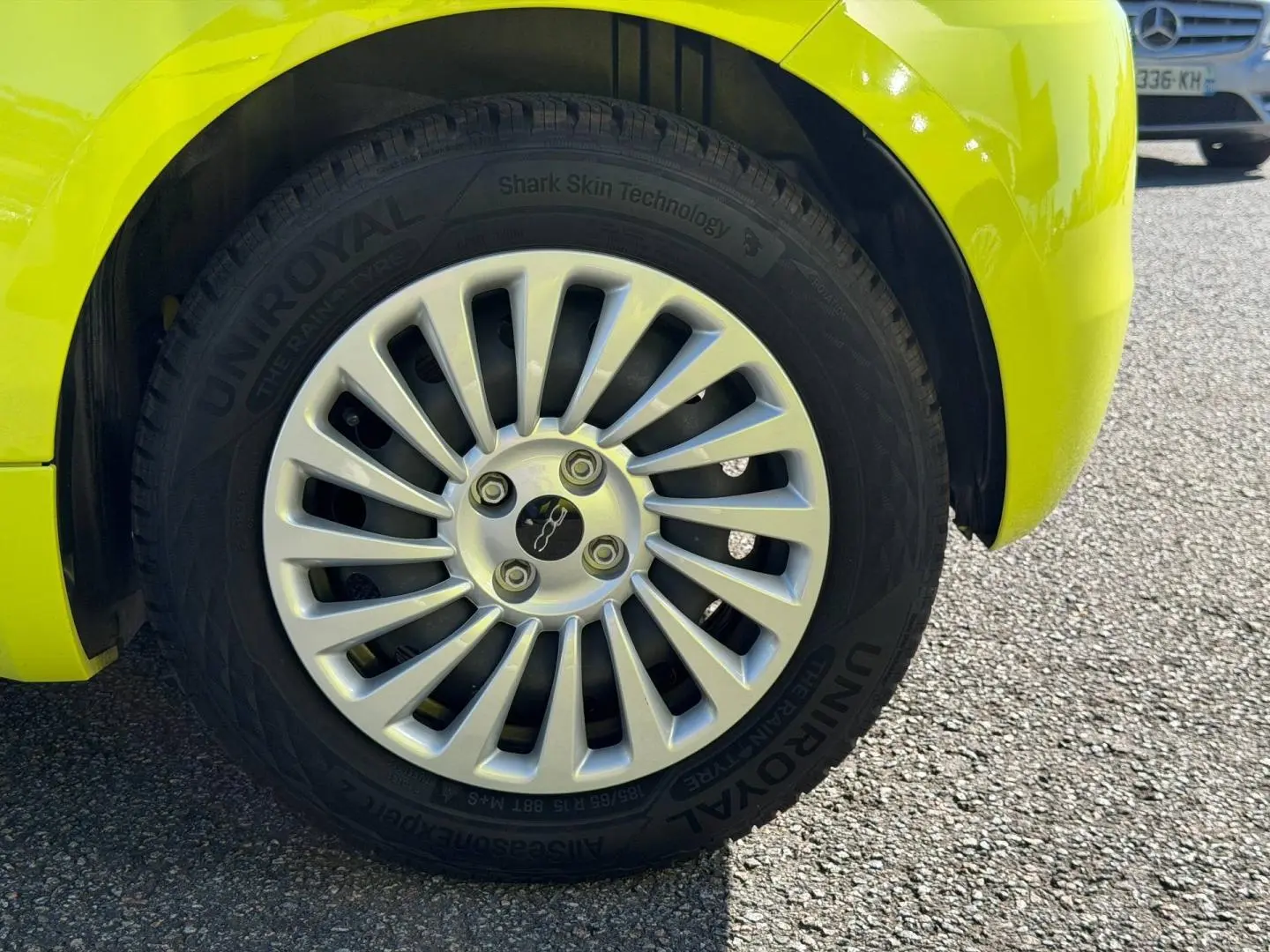 Gros plan sur la roue avant droite d’une FIAT 500 électrique jaune vif avec jante argentée à rayons fins.