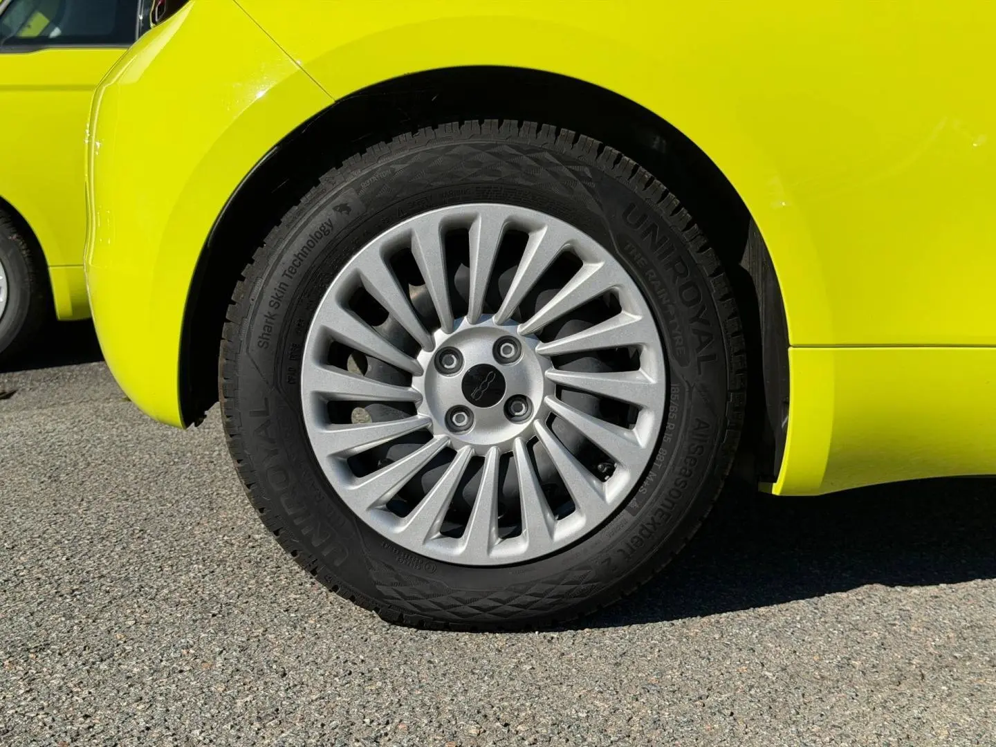 Gros plan sur la roue arrière droite d'une FIAT 500 électrique 2024 en jaune vif avec jante argentée à rayons fins.
