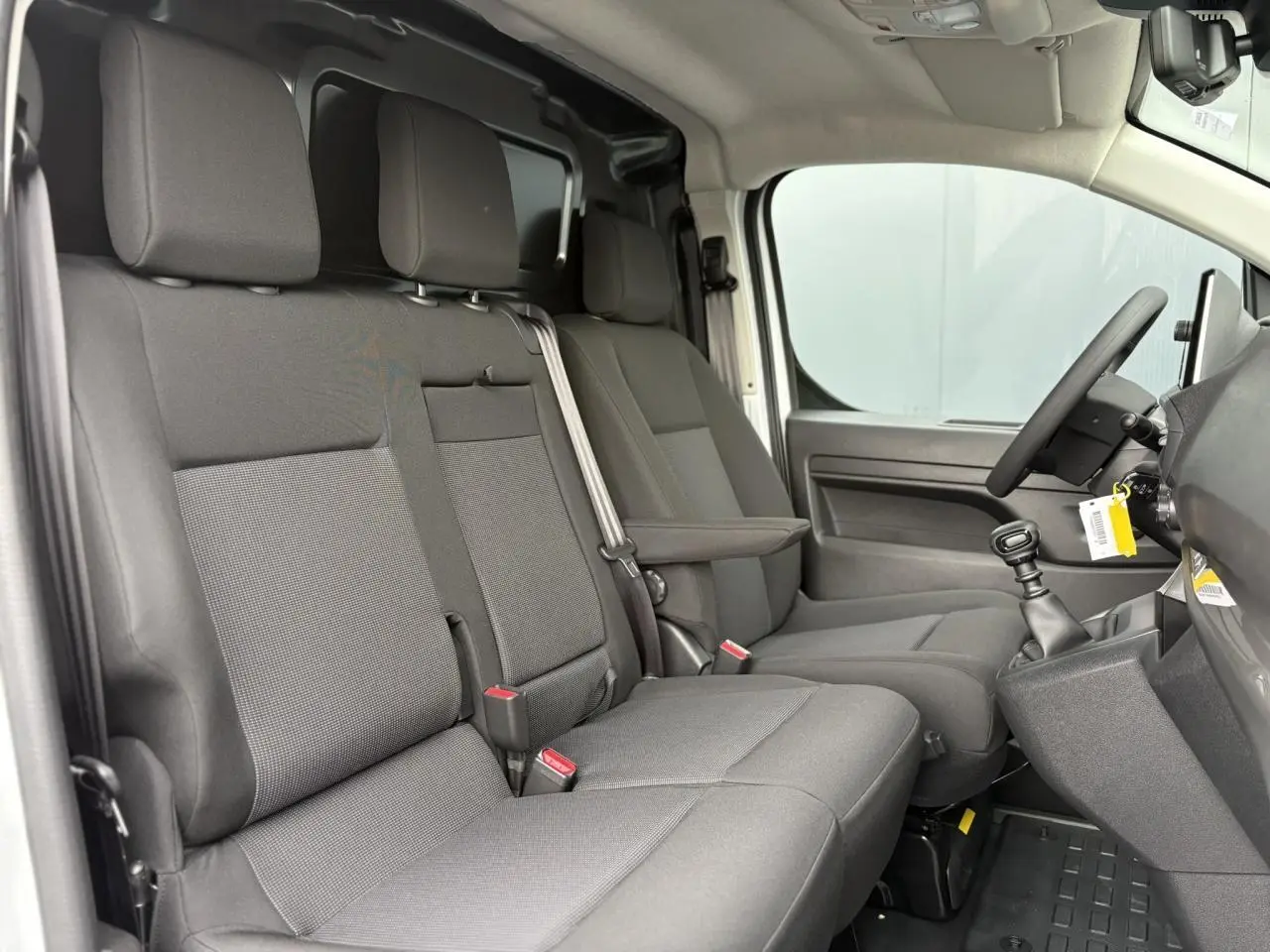 Vue intérieure côté droit du Peugeot Expert Fourgon 2025, montrant la banquette tissu bi-ton noir et gris avec siège conducteur individuel.