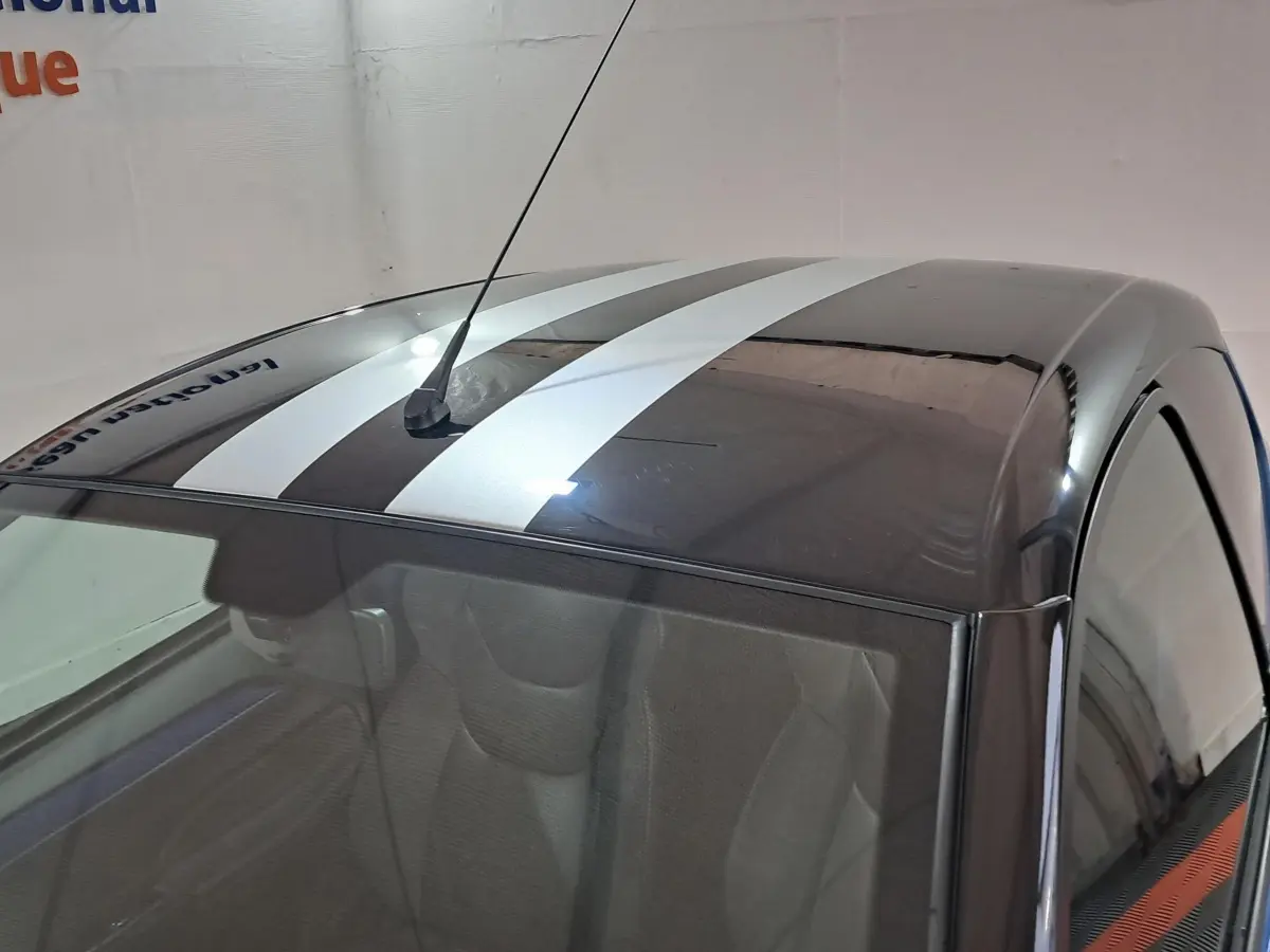 Vue plongeante sur le toit noir brillant d'une Aixam Ambition 2025 avec deux larges bandes blanches sportives.