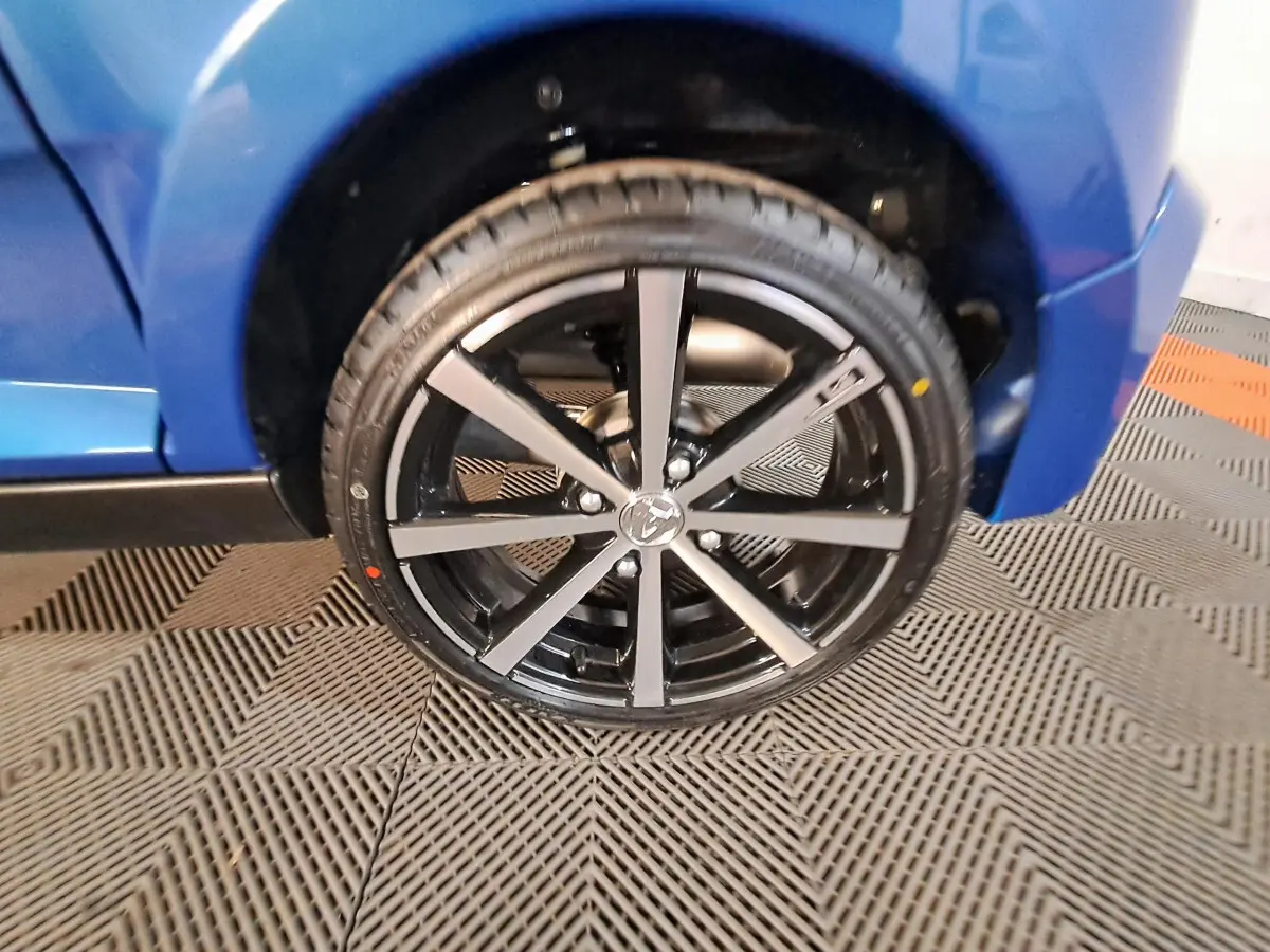 Gros plan sur la roue avant gauche d'une Aixam Ambition bleu 2025 avec jante noire à rayons argentés.