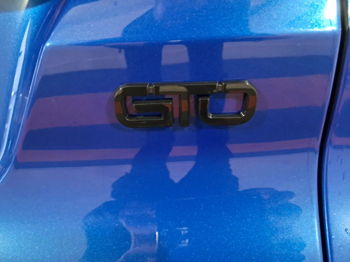 Gros plan sur l’inscription GTO noire sur la carrosserie bleue métallisée de l’AIXAM AMBITION 2025.