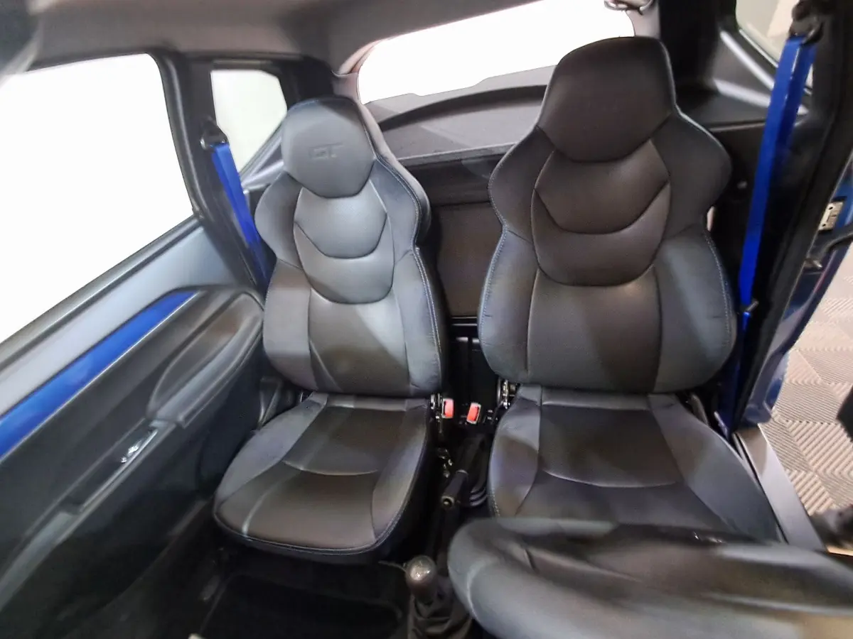 Intérieur de l'AIXAM AMBITION 2025 montrant les sièges sport noirs avec ceinture bleue côté gauche.