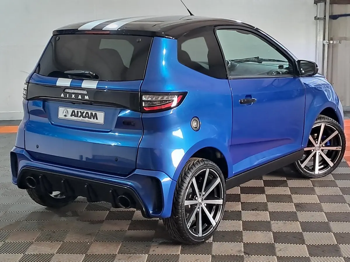 Vue 3/4 arrière droite d'une Aixam Ambition 2025 bleu métallisé avec jantes alliage et double sortie d'échappement.