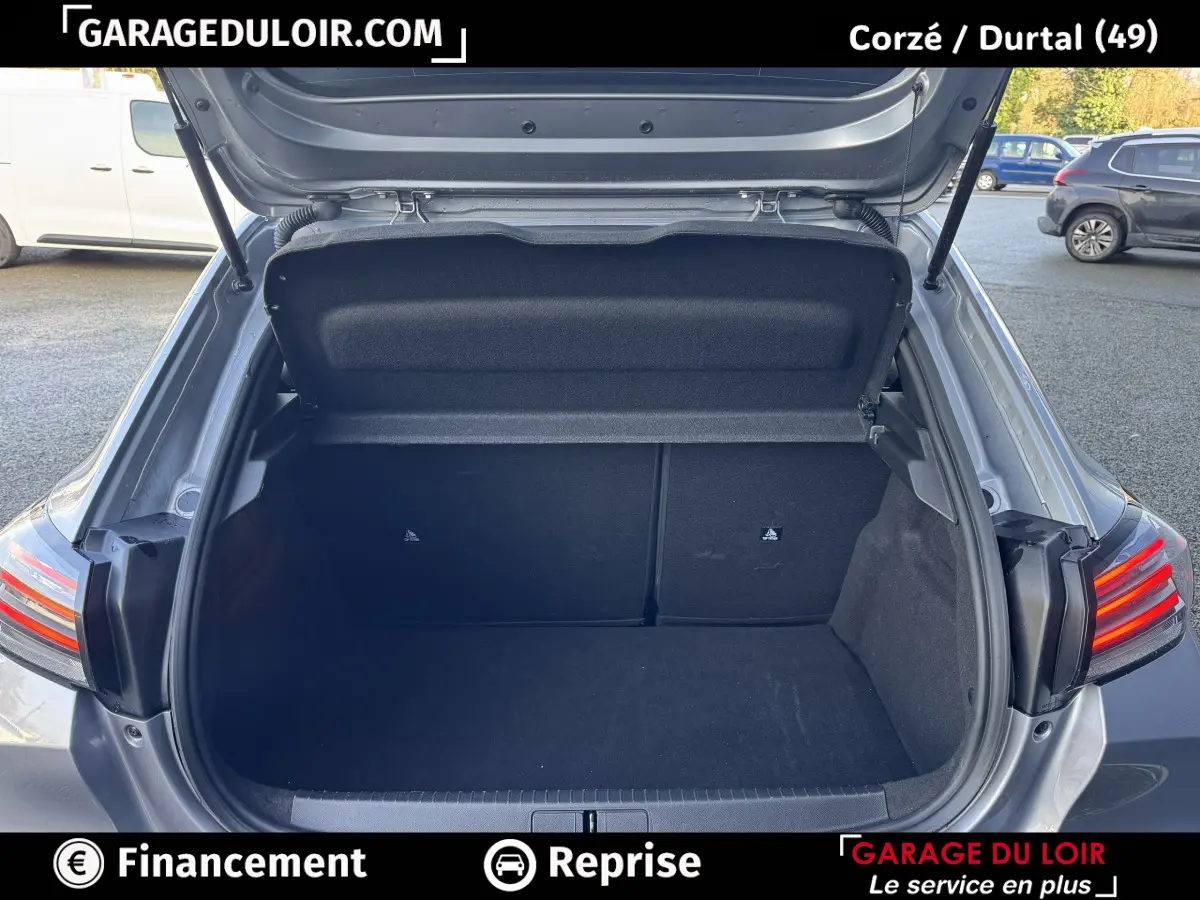 Coffre ouvert vu de l'arrière d'une Peugeot 208 Hybrid 110 gris clair, feux arrière LED visibles.