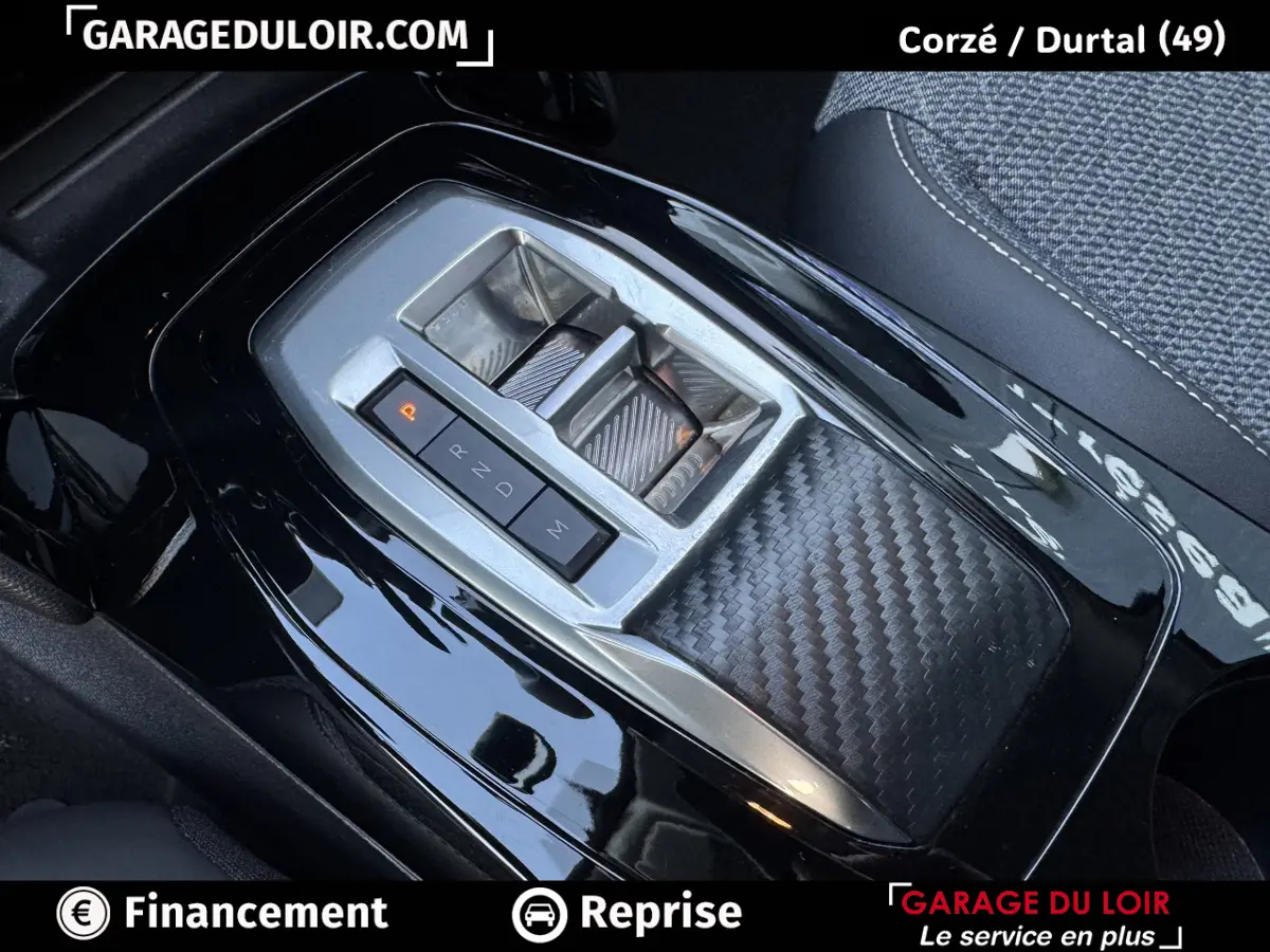 Gros plan sur la console centrale noire brillante de la Peugeot 208 Hybrid 110, avec levier de vitesses automatique et finition carbone.