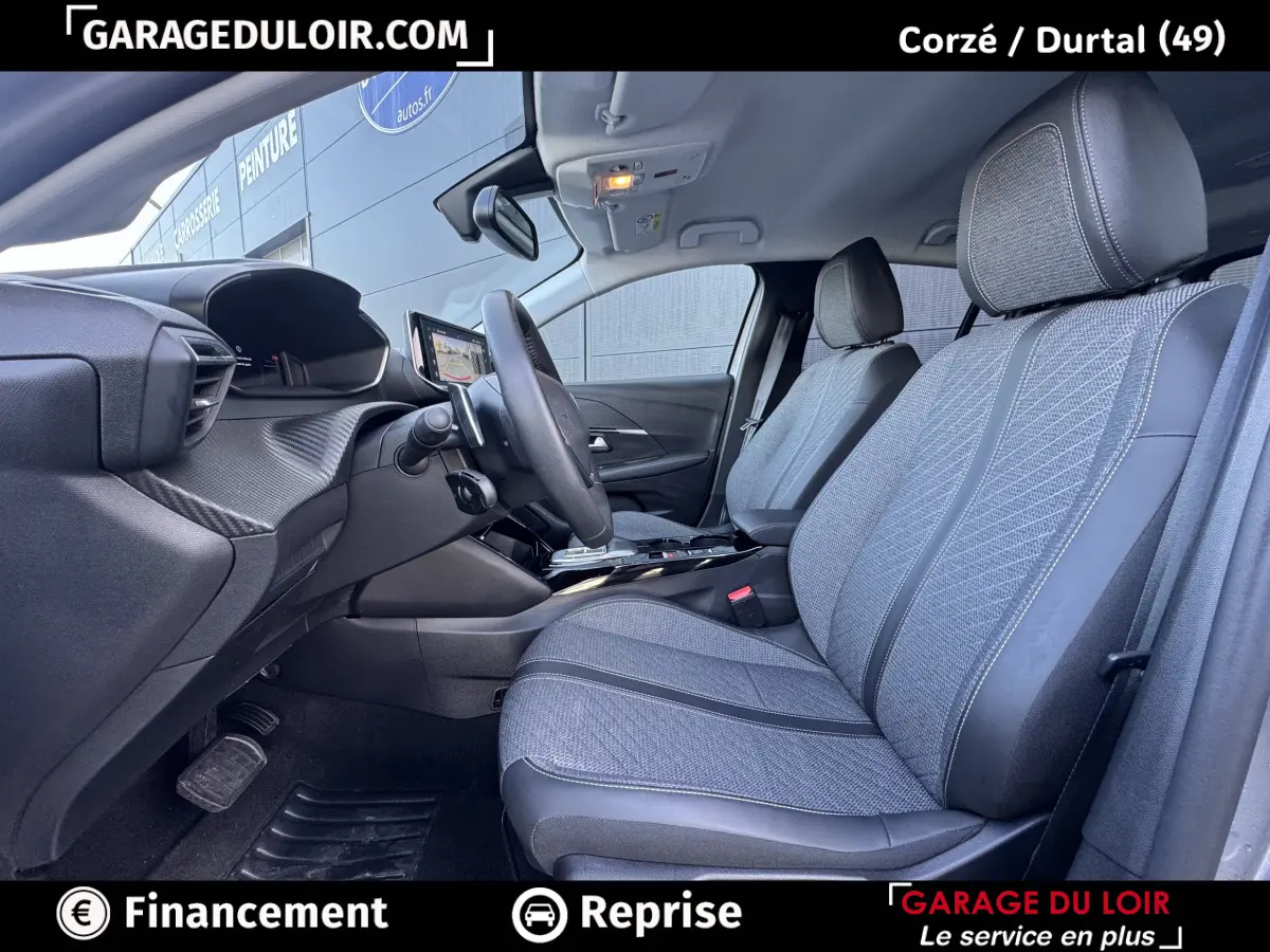 Vue intérieure côté conducteur de la Peugeot 208 Hybrid 110 Allure, sièges tissu gris et volant cuir multifonctions.