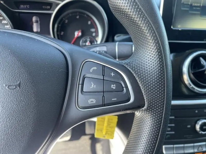 Gros plan sur les commandes du volant côté gauche du Mercedes Classe CLA Shooting Brake noir, tableau de bord en arrière-plan.