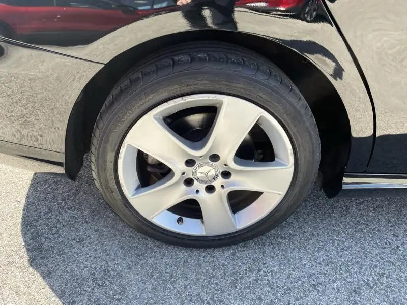 Gros plan sur la roue avant gauche d'une Mercedes Classe CLA Shooting Brake noire, mettant en valeur la jante alliage 5 branches.