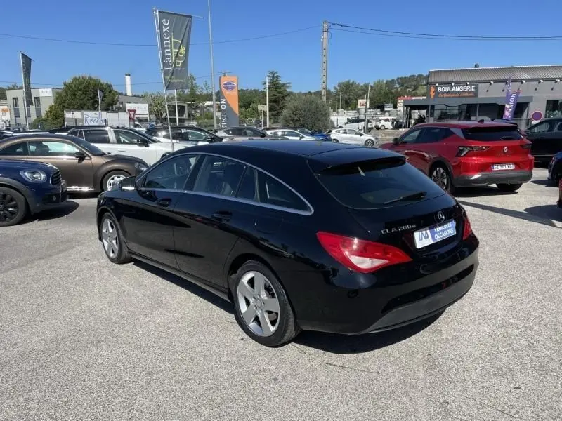 Mercedes Classe CLA Shooting Brake noir vue 3/4 arrière droit sur parking avec feux arrière rouges visibles.