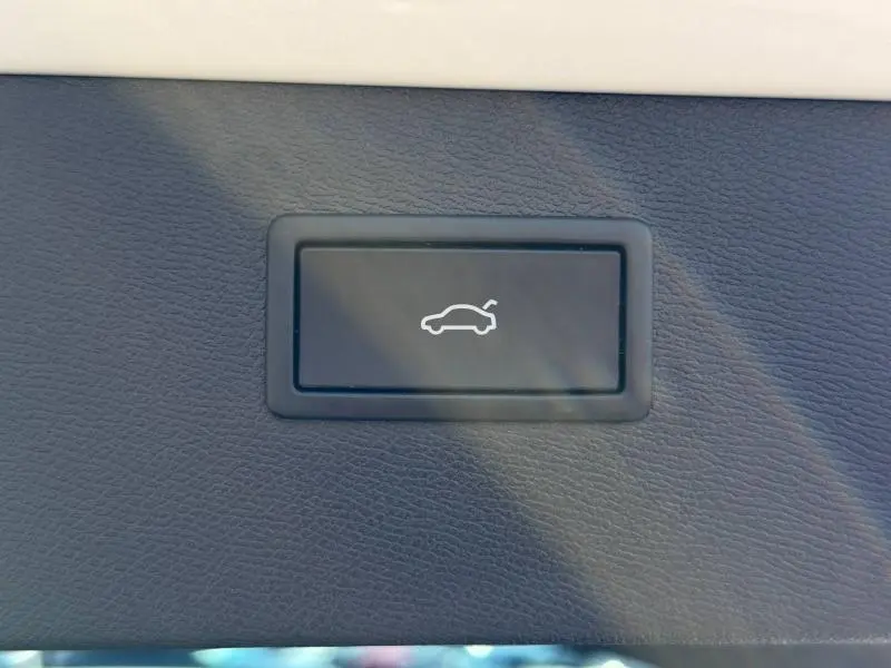 Bouton noir d'ouverture électrique du coffre sur tableau de bord d'une CUPRA Formentor blanc Nevada métallisé.