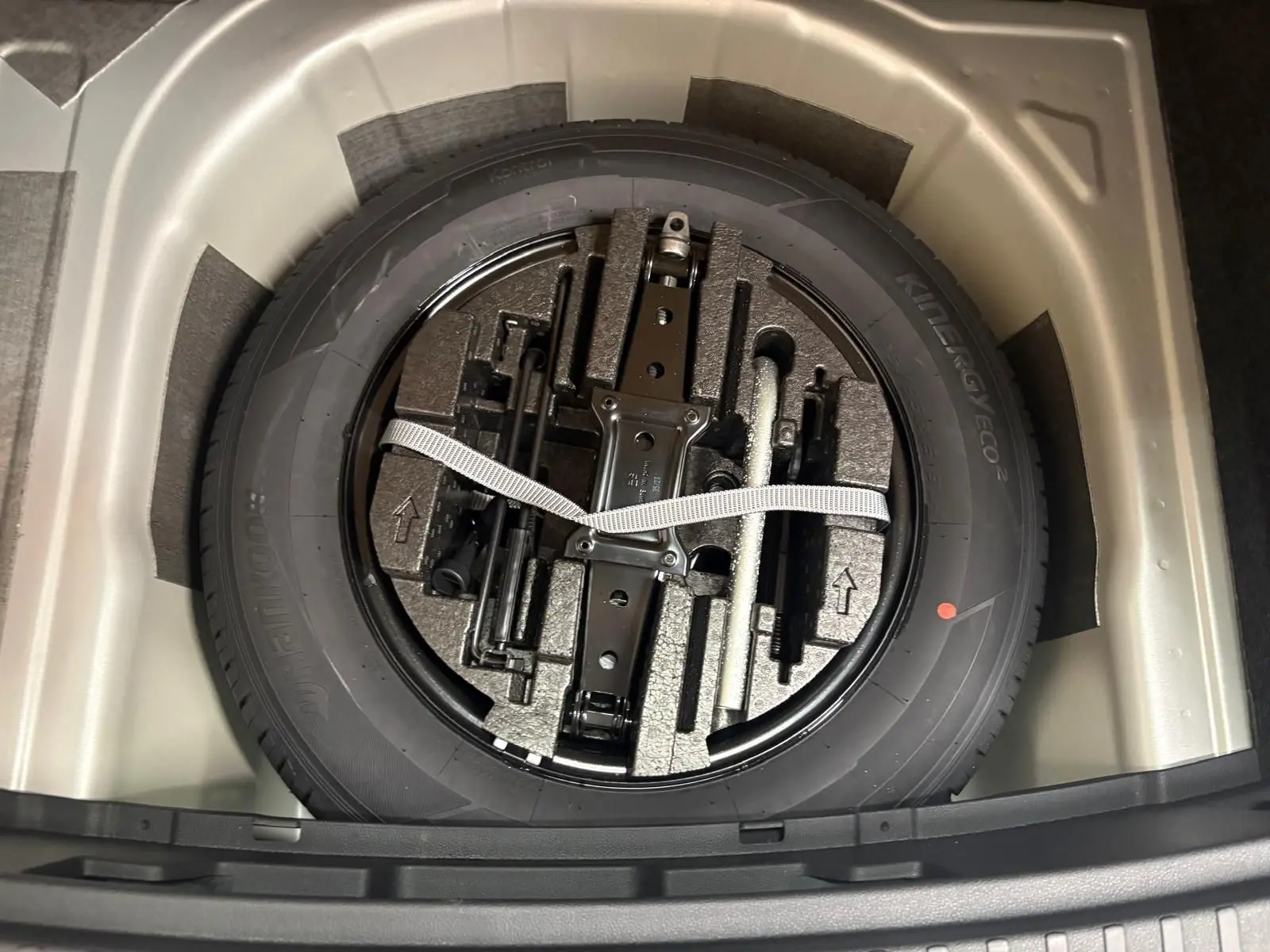 Vue plongeante sur la roue de secours et ses outils dans le coffre du Skoda Scala gris argent 2024.