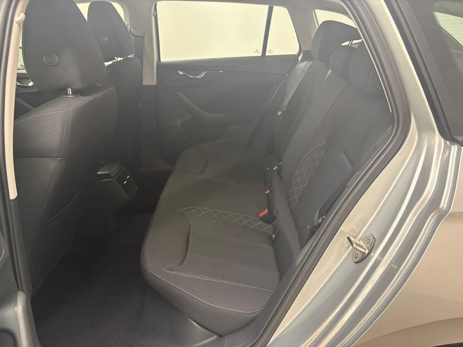 Vue intérieure arrière côté droit de la Skoda Scala 2024 gris argent, montrant les sièges arrière en tissu noir avec surpiqûres.