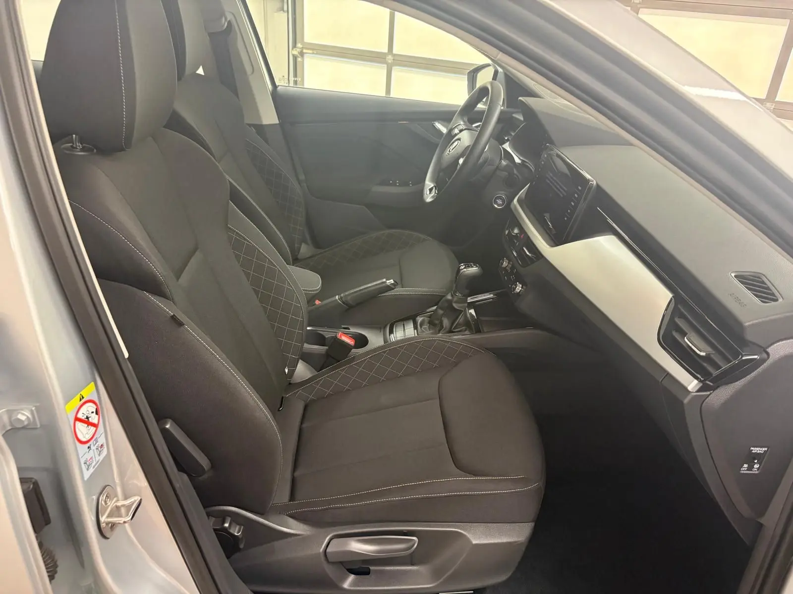 Intérieur côté conducteur de la Skoda Scala 2024 gris argent, sièges noirs avec surpiqûres et tableau de bord moderne.