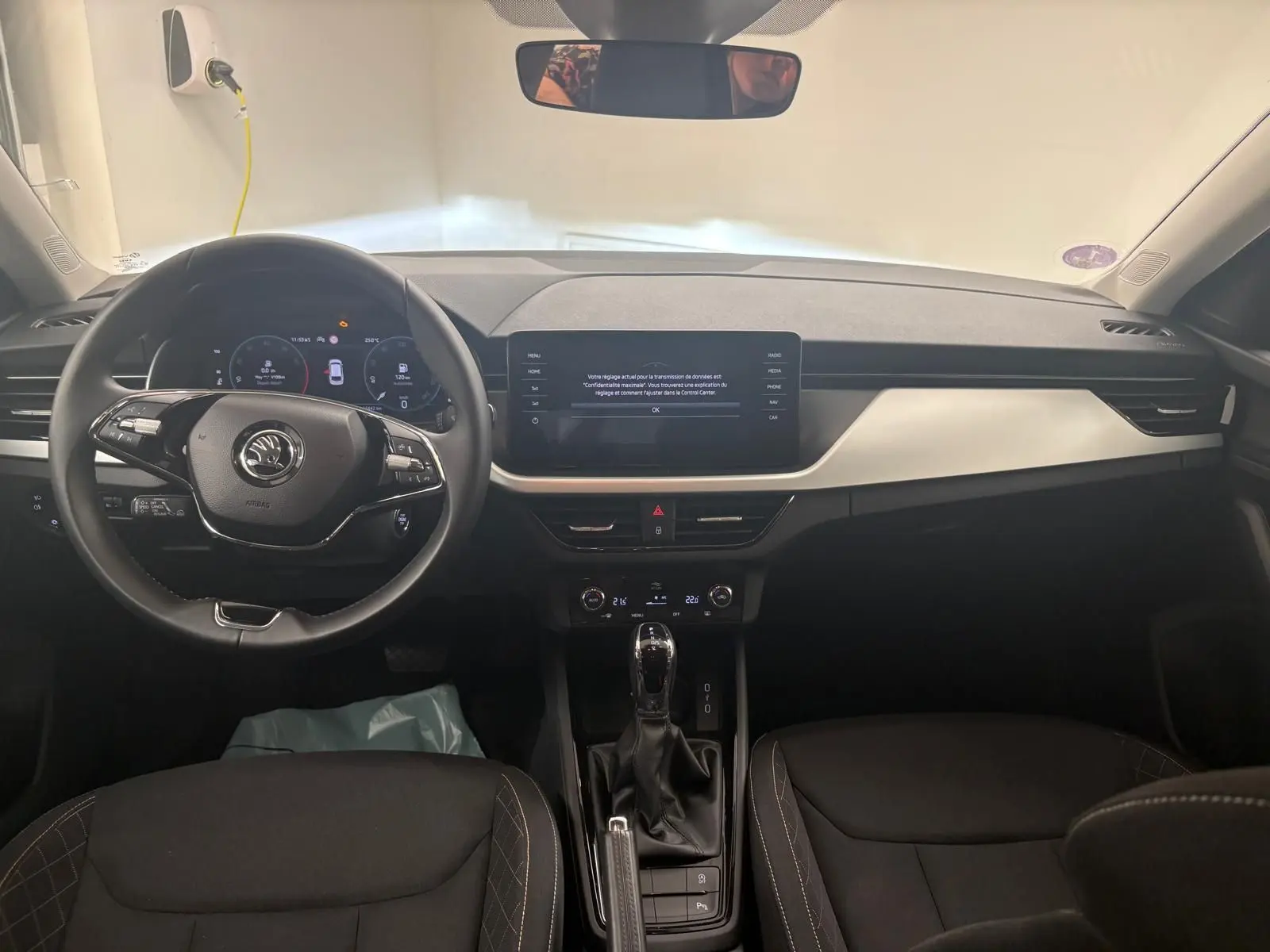 Vue intérieure frontale du tableau de bord de la Skoda Scala 2024 gris argent avec écran tactile et volant multifonction.
