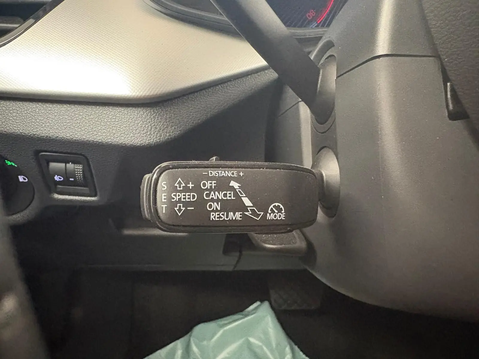 Gros plan sur la commande de régulateur de vitesse à gauche du volant dans l’habitacle gris du Skoda Scala 2024.