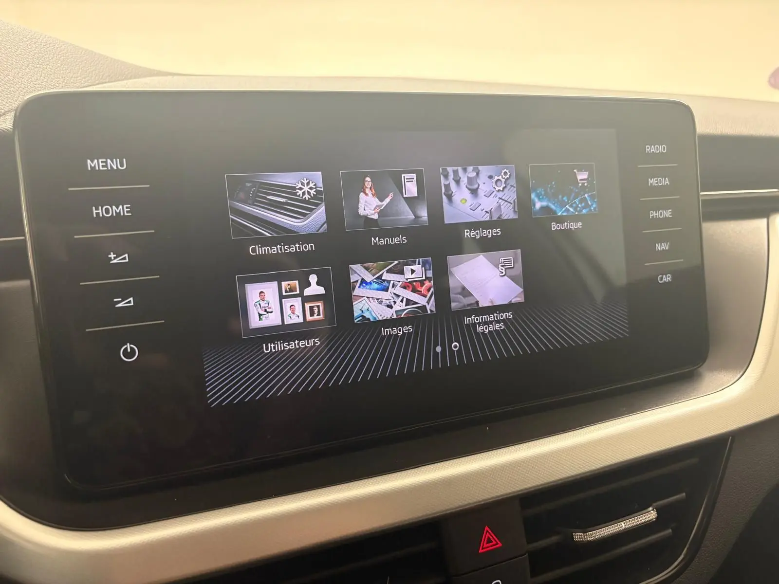 Écran tactile central du Skoda Scala 2024 affichant le menu principal avec options climatisation, manuels et réglages.