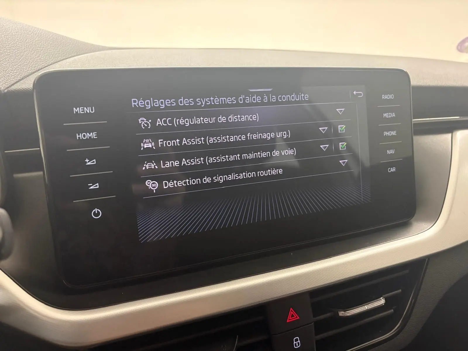 Écran tactile central du Skoda Scala 2024 gris argent affichant les réglages des aides à la conduite.