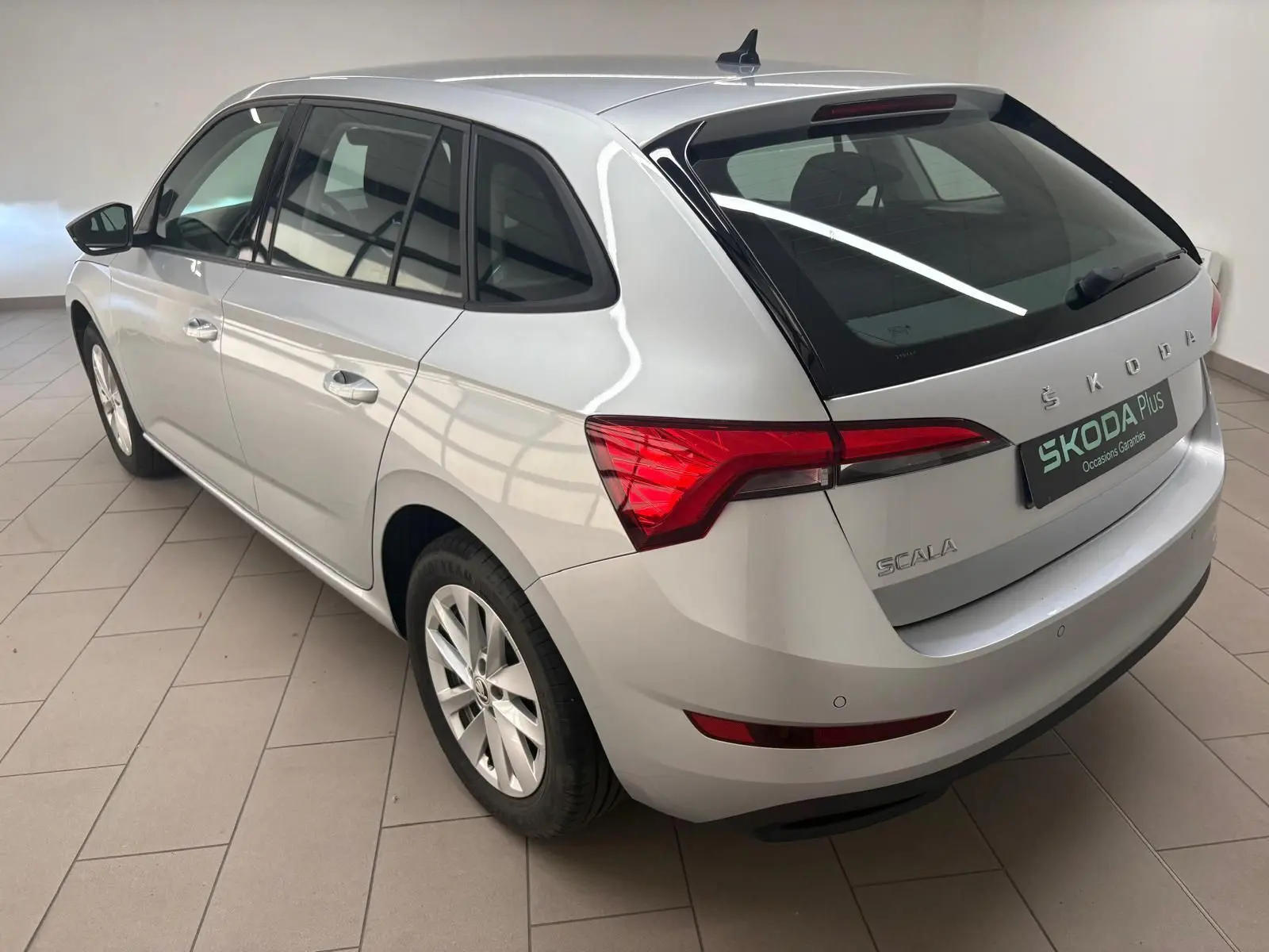Vue 3/4 arrière droite d'une Skoda Scala gris argent 2024 avec feux arrière LED et jantes alliage.