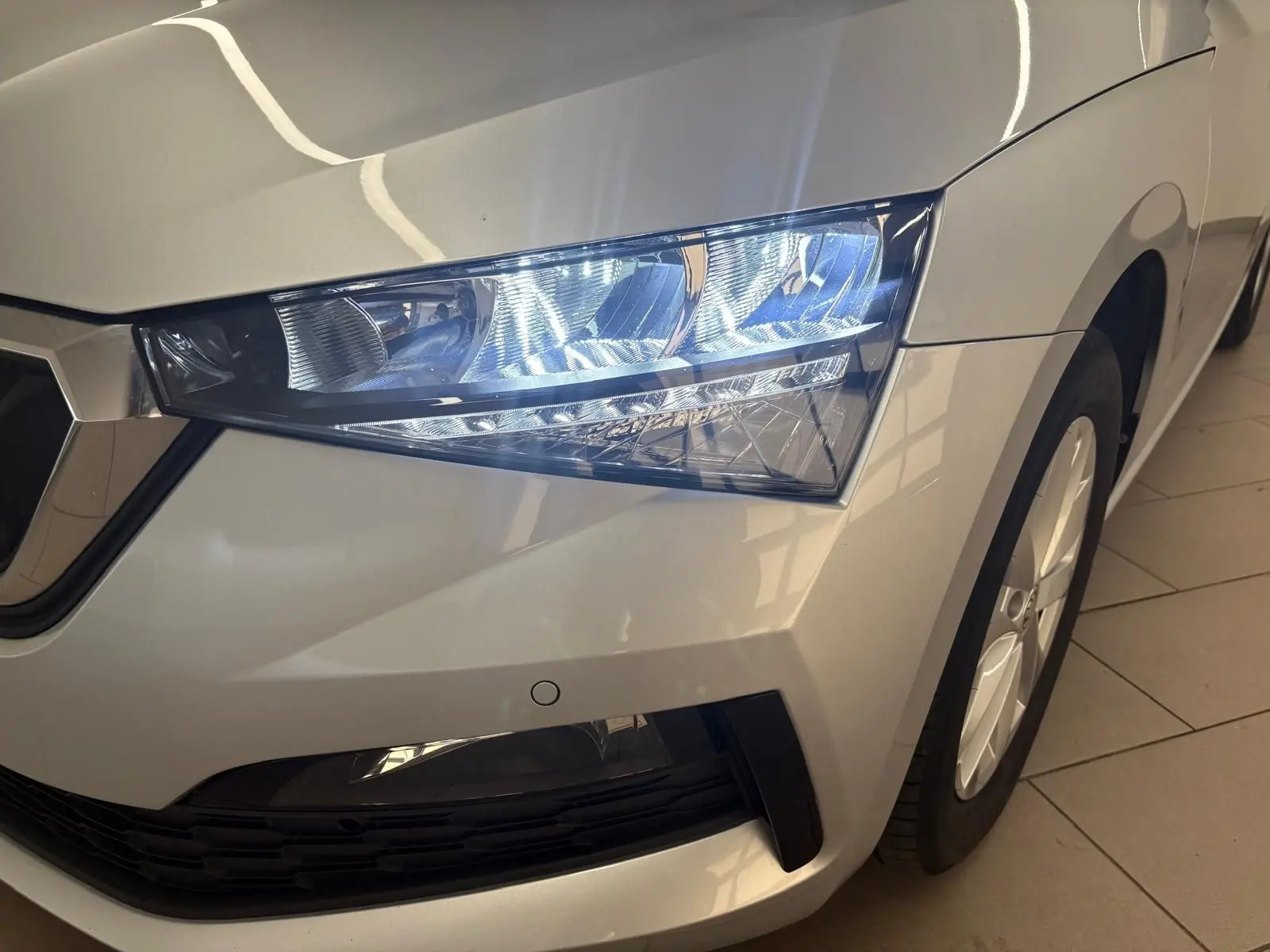 Gros plan sur le phare avant droit d'une Skoda Scala gris argent 2024 avec jante alliage visible.