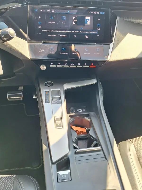 Vue rapprochée de la console centrale et du cockpit numérique de la Peugeot 308 SW Hybrid 145 e-DCS6 GT 2025, intérieur noir.