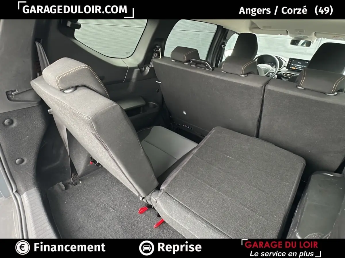 Vue arrière intérieure du Dacia Jogger Extreme+ Hybrid 140 2025, sièges arrière partiellement rabattus en tissu gris foncé.