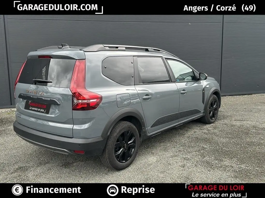 Vue 3/4 arrière droite d'un Dacia Jogger Extreme+ Hybrid 140 gris avec jantes noires et vitres teintées.