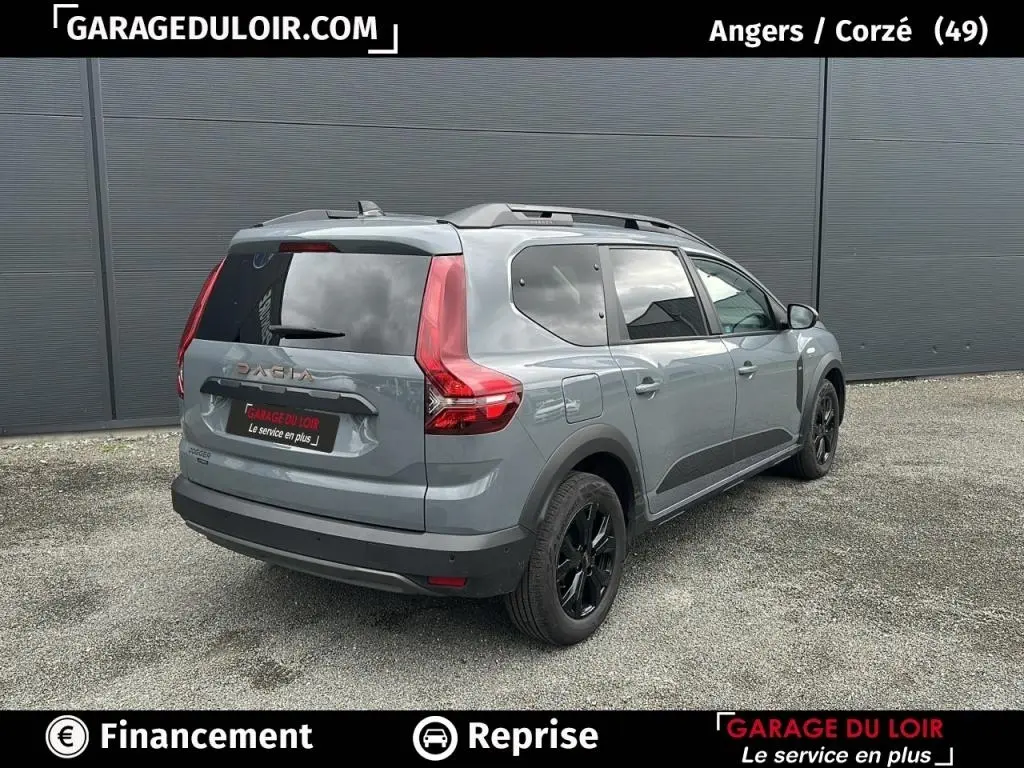 Vue 3/4 arrière droite d'un Dacia Jogger Extreme+ Hybrid 140 2025 gris avec jantes noires et barres de toit.
