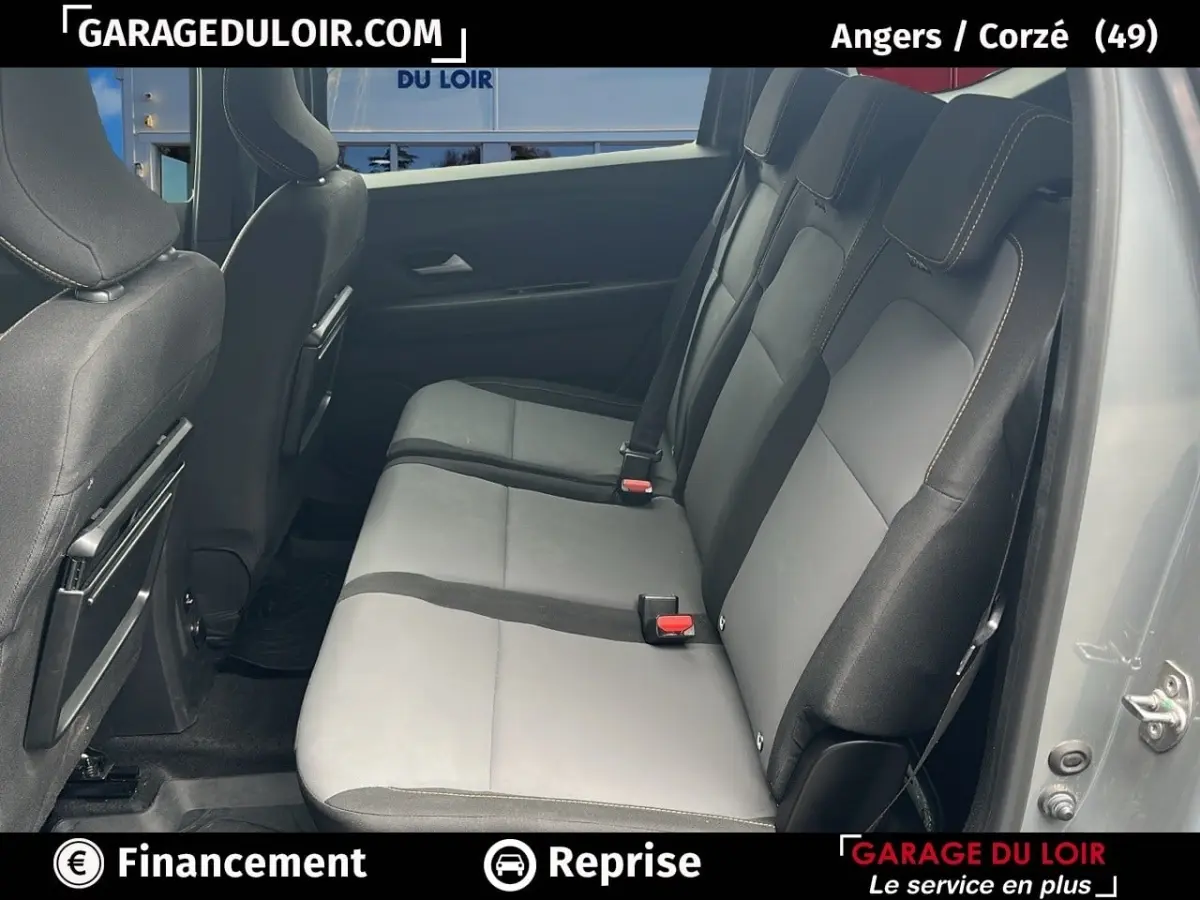 Vue latérale droite des sièges arrière gris clair et noir du Dacia Jogger Extreme+ Hybrid 140 2025 avec portes ouvertes.