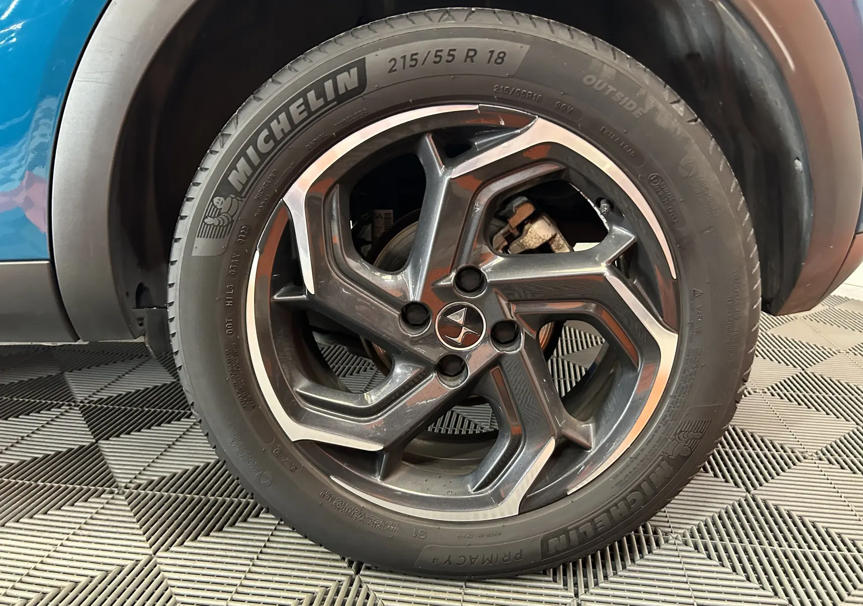 Gros plan sur la roue avant droite d’un DS3 Crossback Bleu Millenium avec jante alliage noire et argentée.