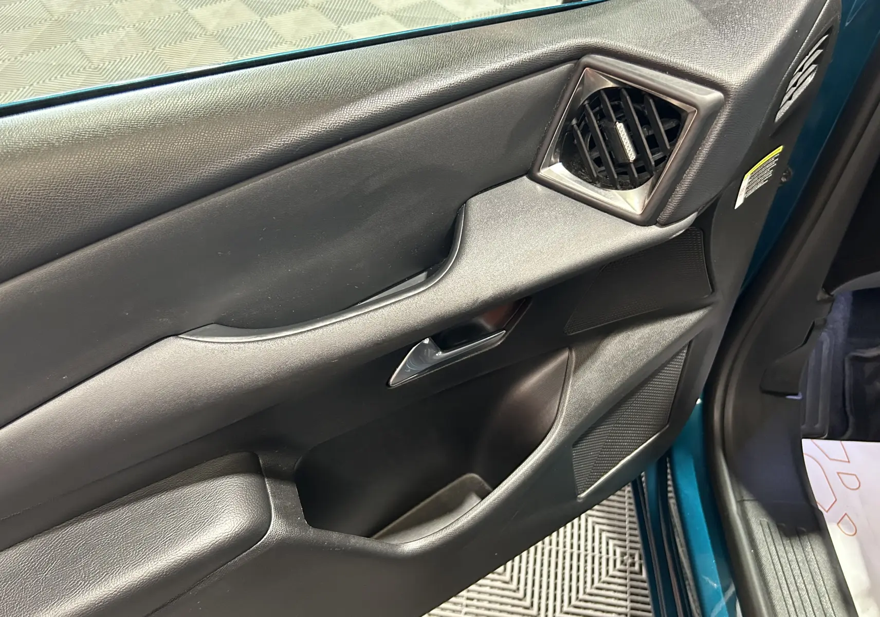 Vue intérieure côté gauche de la porte avant d'une DS3 Crossback Bleu Millenium avec garniture noire et aérateurs angulaires.