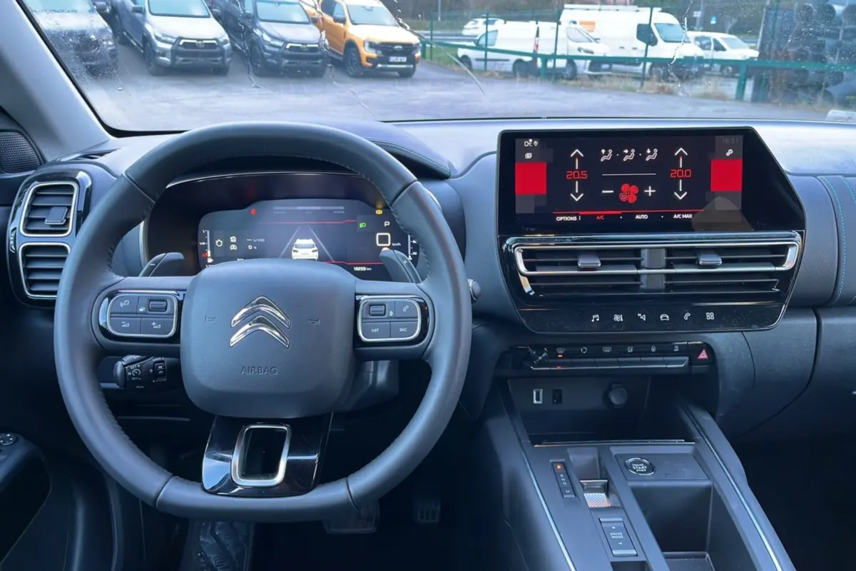 Vue intérieure du poste de conduite du Citroën C5 Aircross Hybrid blanc, avec volant multifonctions et écran tactile central.