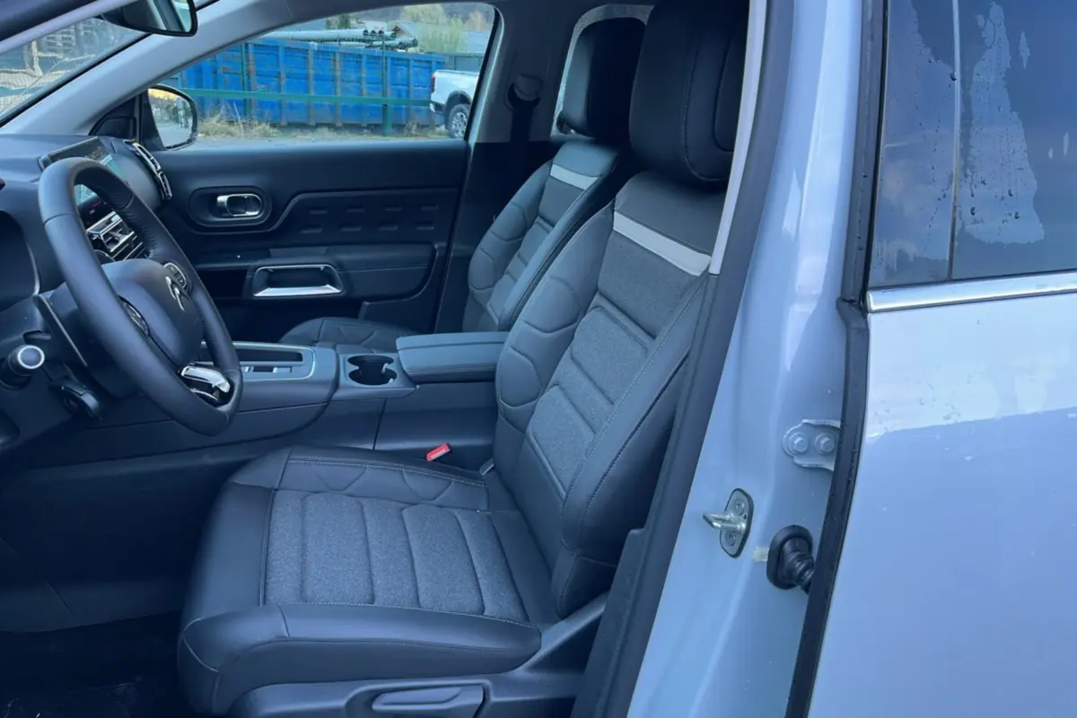 Vue intérieure côté conducteur du Citroën C5 Aircross blanc okénite, sièges avant en cuir et tissu gris avec accoudoir central.